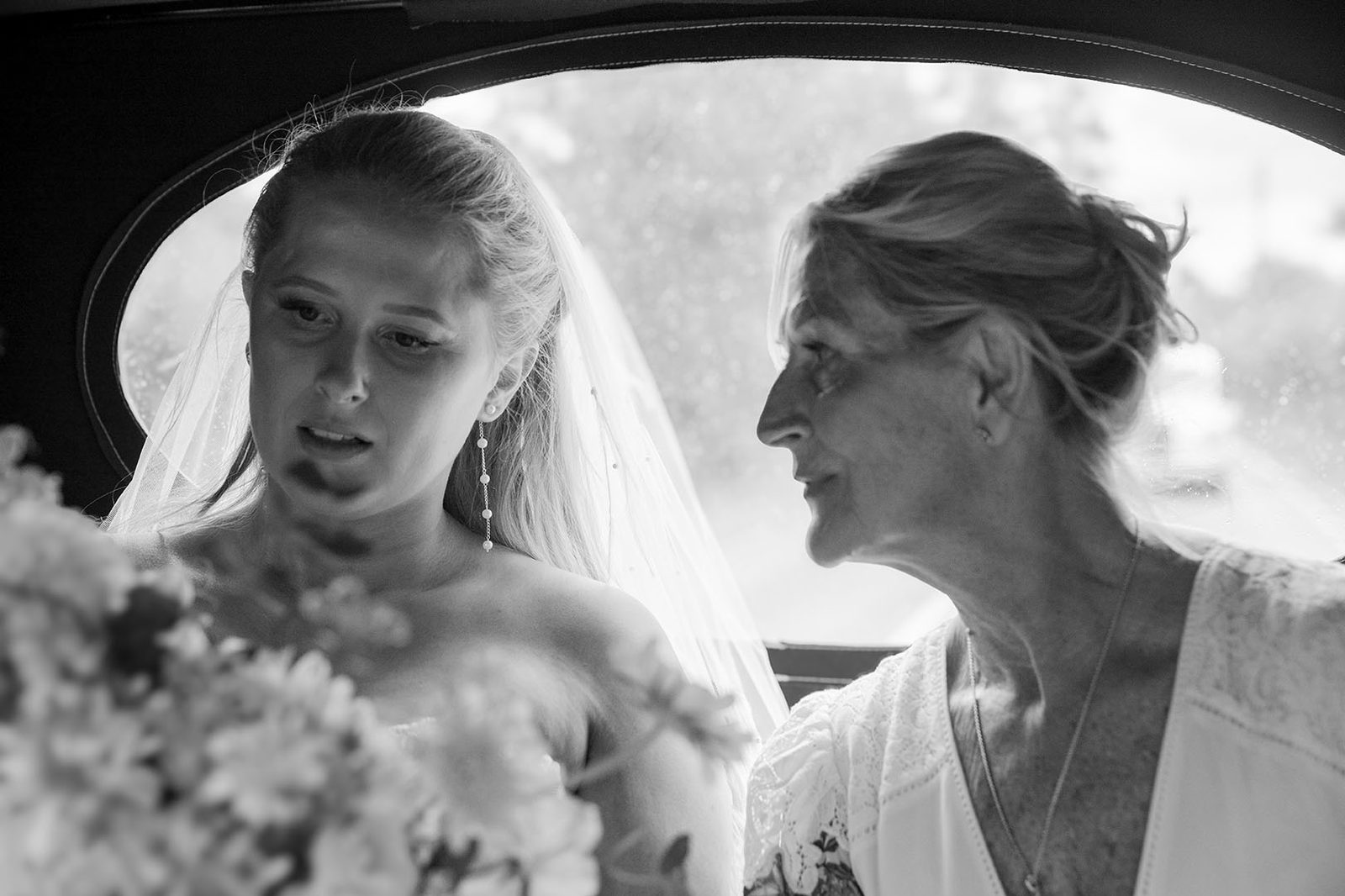 A bride and family member sharing a moment in a wedding car