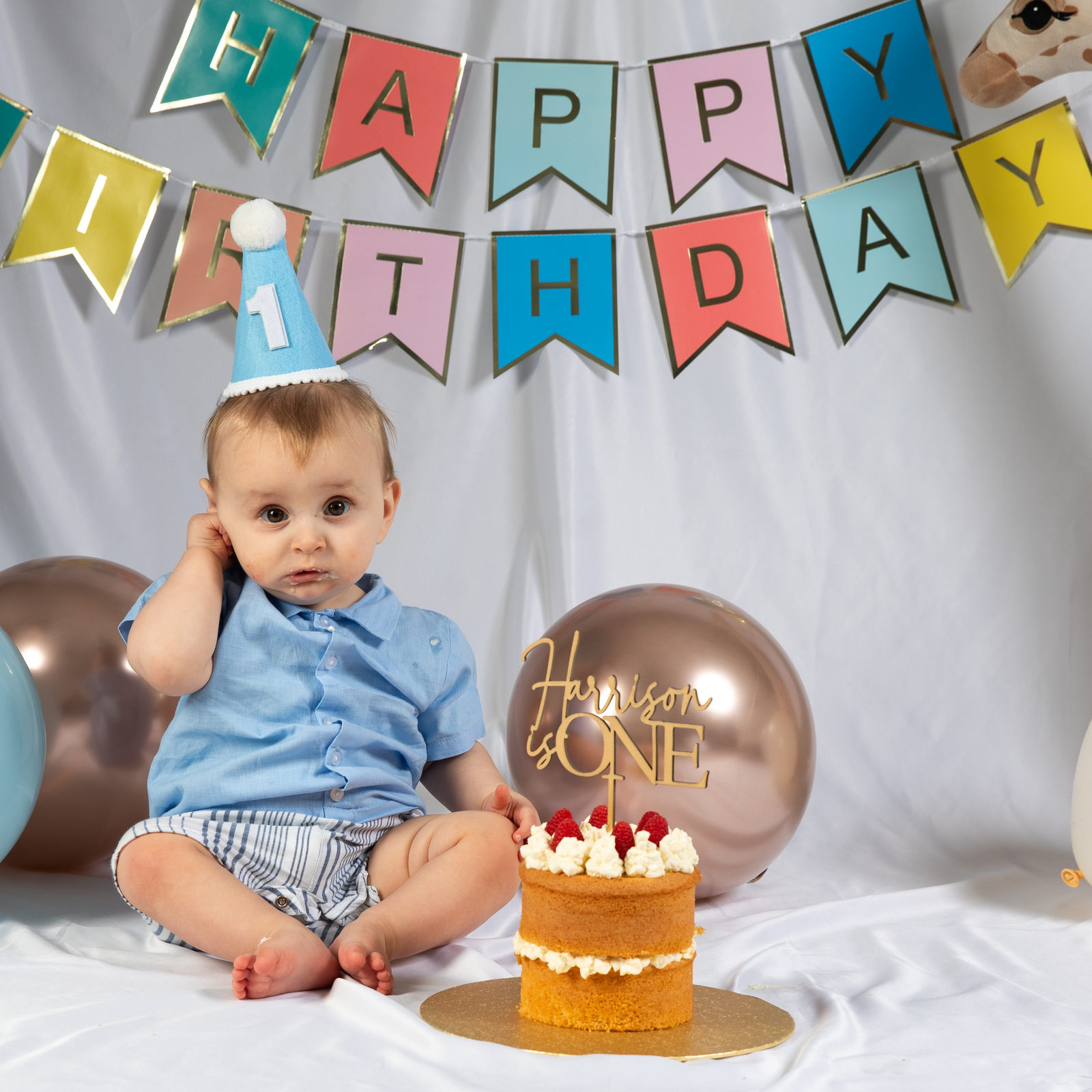 A one-year-old sitting beside a birthday cake