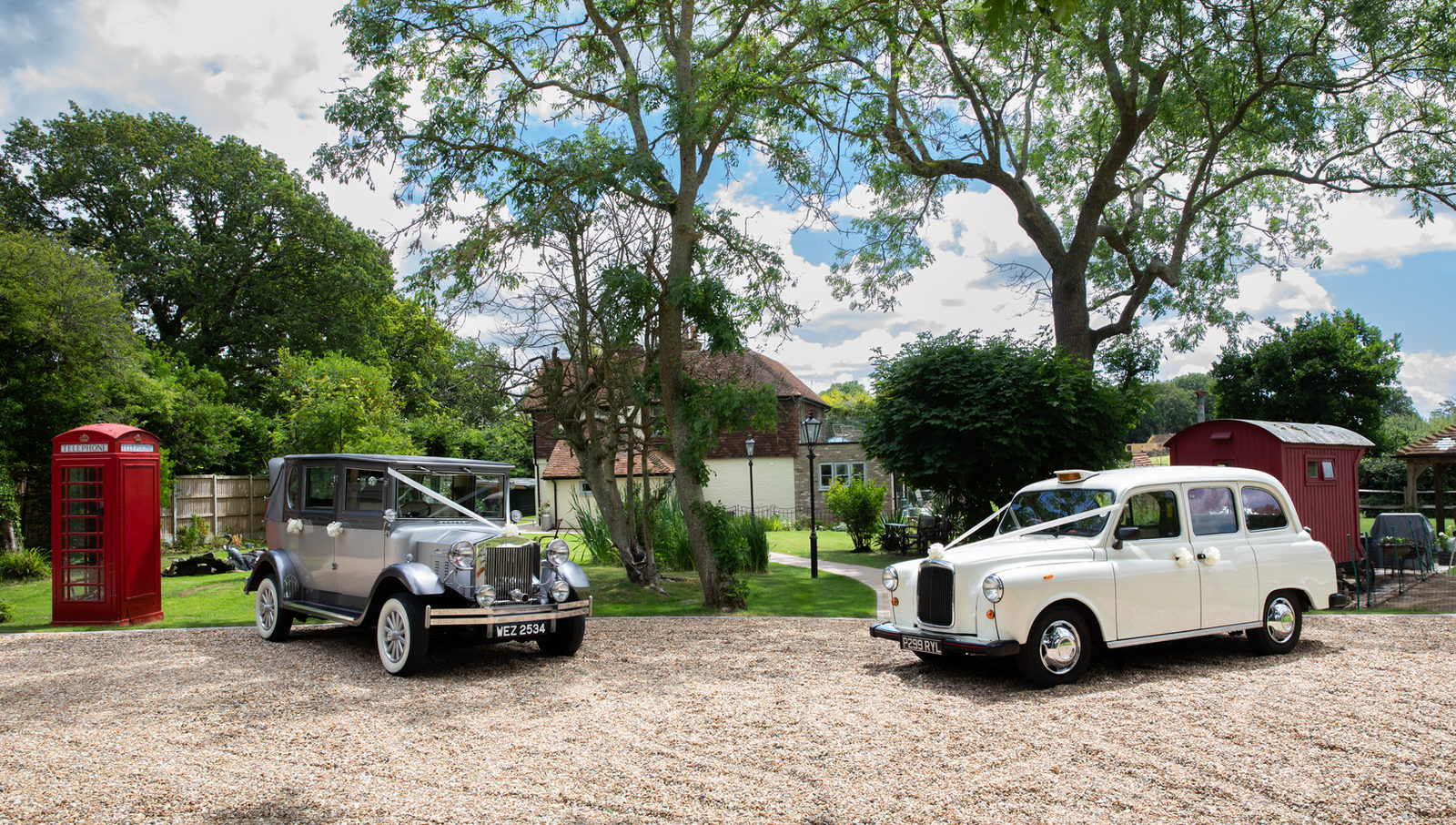 Two decorated classic wedding cars outside a country venue