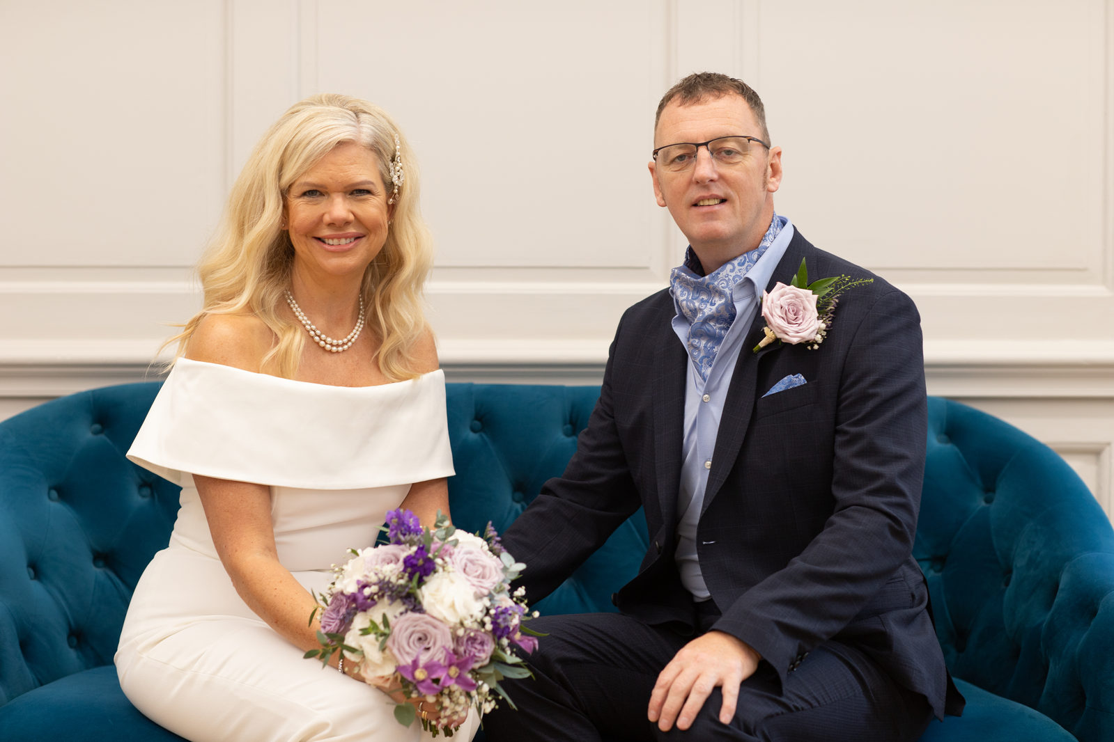 A newly married couple seated together with a bouquet