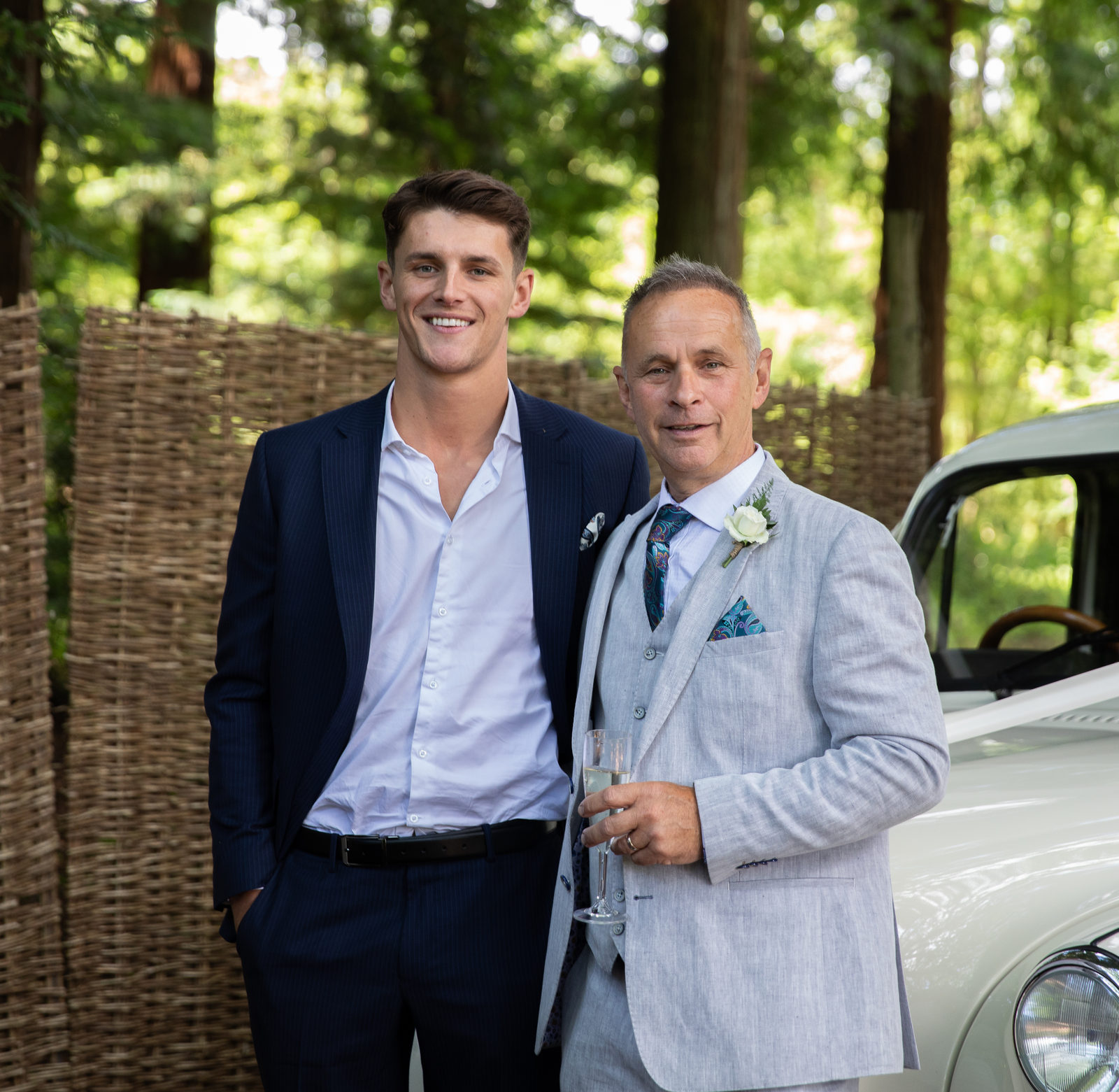 Two wedding guests standing beside a classic car