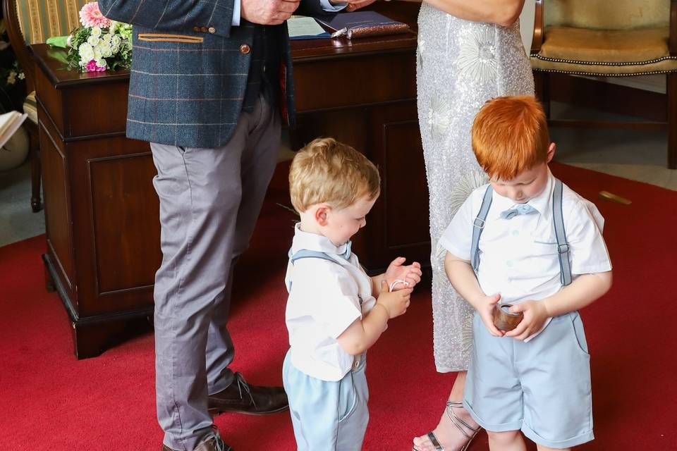 Two young wedding attendants looking at their hands during a ceremony