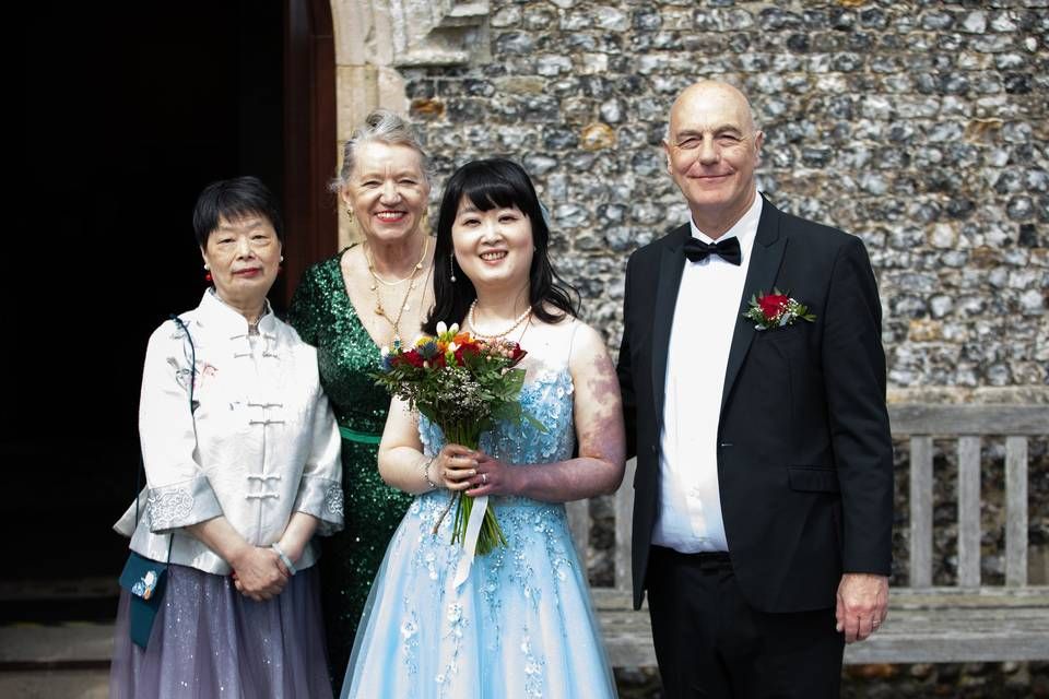 A newly married couple standing with family outside a stone church