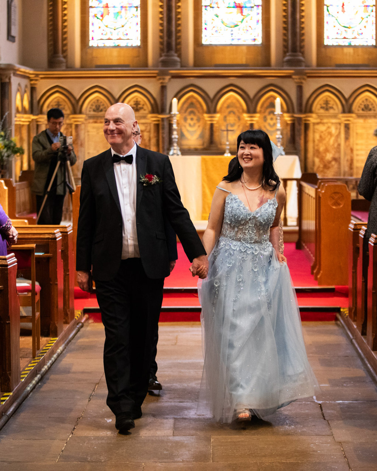 A newly married couple walking hand in hand down a church aisle